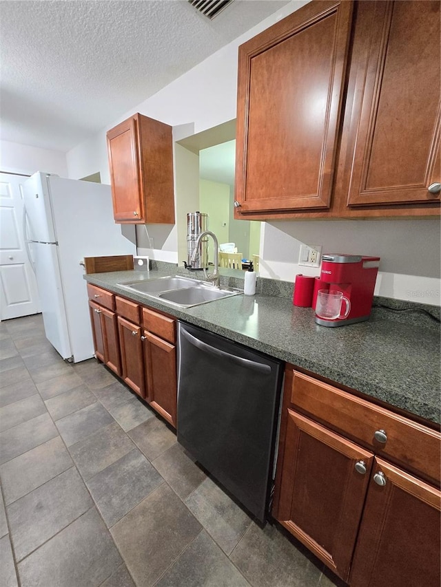 kitchen featuring sink, dark tile patterned flooring, a textured ceiling, and stainless steel dishwasher