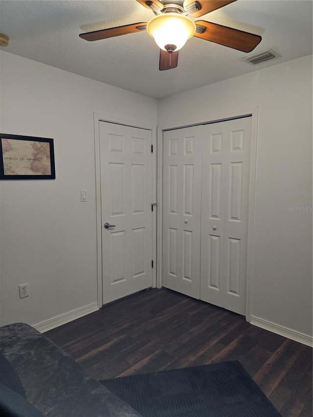 unfurnished bedroom with a closet, dark hardwood / wood-style flooring, and ceiling fan