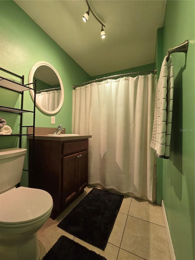 bathroom with tile patterned flooring, vanity, toilet, and rail lighting