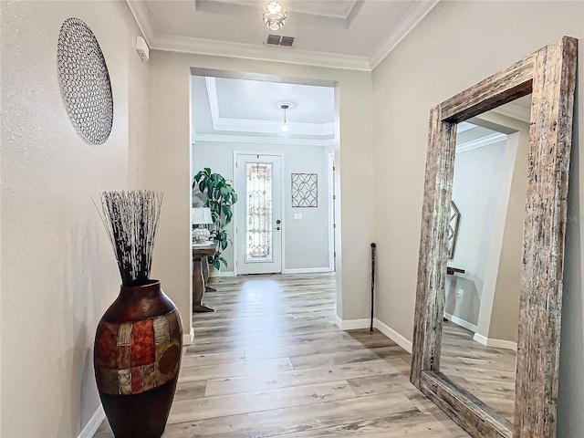 foyer entrance featuring ornamental molding, light hardwood / wood-style floors, and a tray ceiling