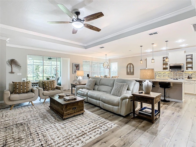 living room with ceiling fan, crown molding, and light hardwood / wood-style floors