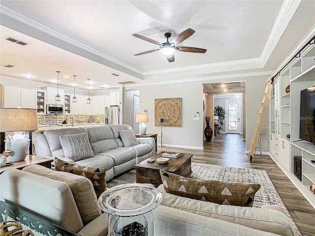 living room with ceiling fan, dark hardwood / wood-style flooring, a raised ceiling, and ornamental molding