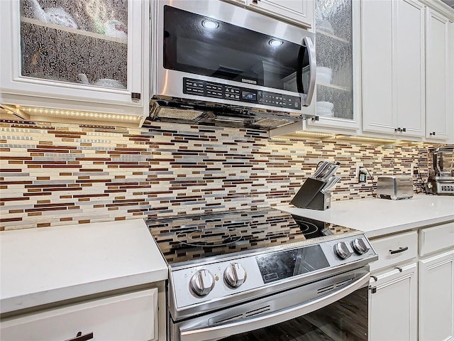 kitchen with white cabinets, tasteful backsplash, and stainless steel appliances