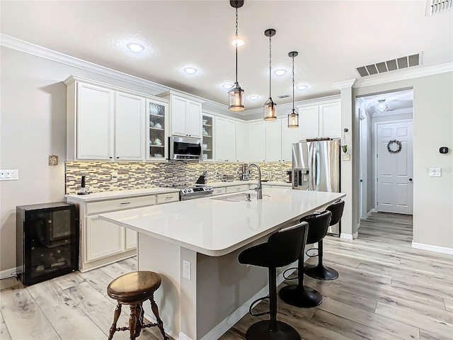 kitchen with white cabinetry, sink, a breakfast bar, stainless steel appliances, and a center island with sink