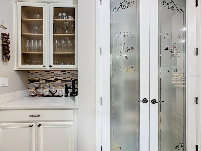 bar with white cabinets and decorative backsplash