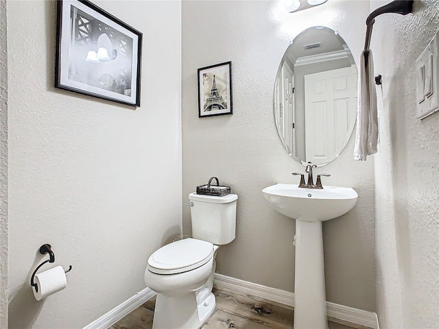 bathroom featuring hardwood / wood-style flooring, toilet, and ornamental molding