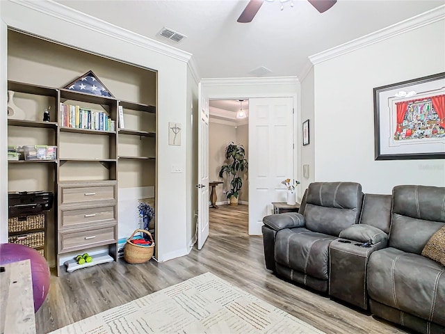 living room featuring ceiling fan, built in features, crown molding, and light hardwood / wood-style flooring