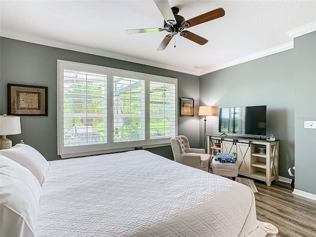 bedroom featuring multiple windows, hardwood / wood-style flooring, ceiling fan, and ornamental molding