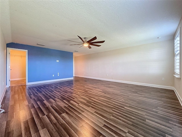 empty room featuring a textured ceiling, ceiling fan, dark hardwood / wood-style flooring, and vaulted ceiling