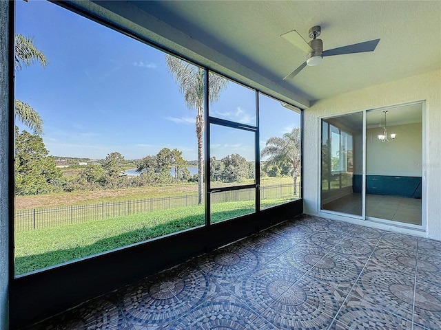 unfurnished sunroom with ceiling fan with notable chandelier