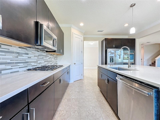 kitchen featuring sink, crown molding, decorative backsplash, appliances with stainless steel finishes, and decorative light fixtures