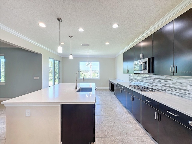 kitchen with sink, hanging light fixtures, appliances with stainless steel finishes, and a center island with sink