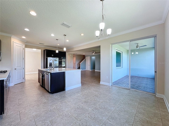 kitchen featuring ceiling fan with notable chandelier, pendant lighting, a textured ceiling, and an island with sink