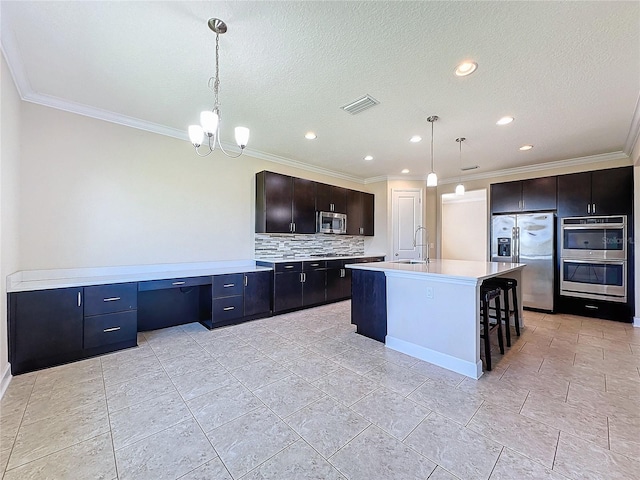 kitchen with tasteful backsplash, pendant lighting, sink, a kitchen island with sink, and stainless steel appliances