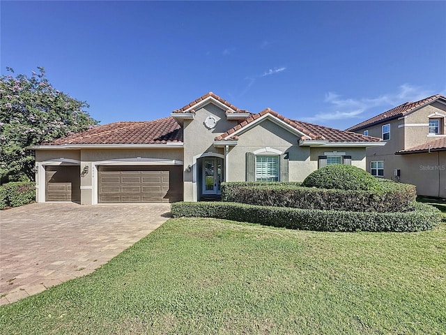 mediterranean / spanish-style home featuring a front lawn and a garage