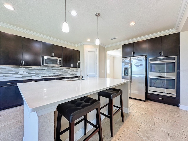 kitchen with dark brown cabinets, sink, stainless steel appliances, and a kitchen island with sink