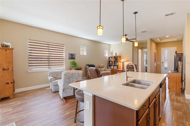 kitchen featuring pendant lighting, sink, light hardwood / wood-style flooring, and a center island with sink