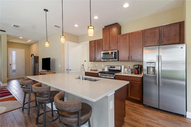 kitchen featuring sink, a breakfast bar area, hanging light fixtures, an island with sink, and stainless steel appliances