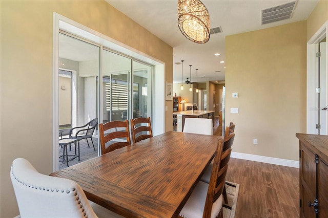 dining room with dark wood-type flooring, sink, and a notable chandelier