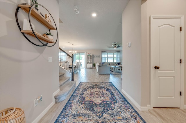 hall with an inviting chandelier and light hardwood / wood-style flooring