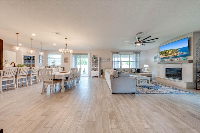 living room featuring plenty of natural light, a large fireplace, and light hardwood / wood-style flooring