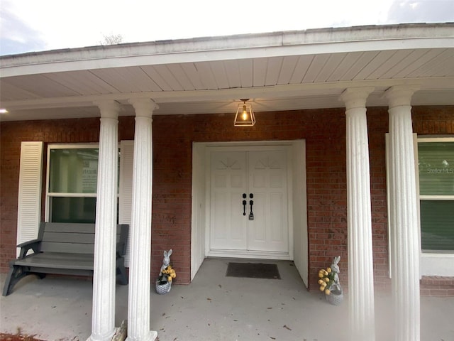 entrance to property with covered porch and brick siding