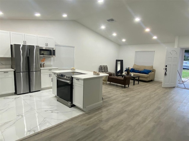 kitchen featuring lofted ceiling, light countertops, appliances with stainless steel finishes, and visible vents