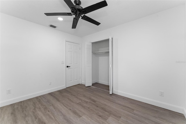 unfurnished bedroom with baseboards, visible vents, a ceiling fan, wood finished floors, and a closet