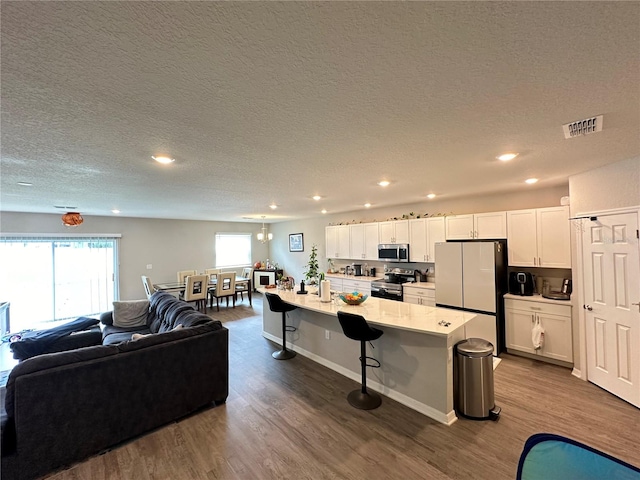 kitchen featuring a kitchen bar, a kitchen island, stainless steel appliances, and hardwood / wood-style floors