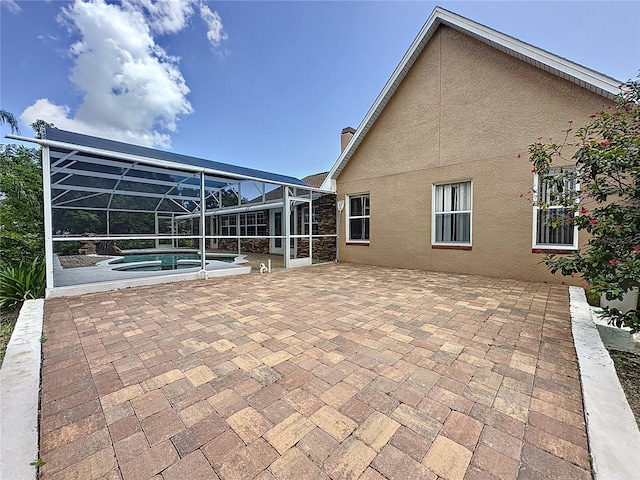 rear view of property with a lanai and a patio area