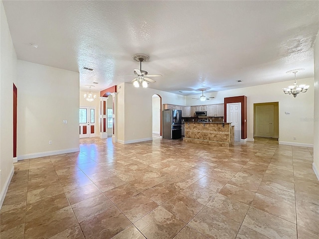 unfurnished living room with ceiling fan with notable chandelier and a textured ceiling