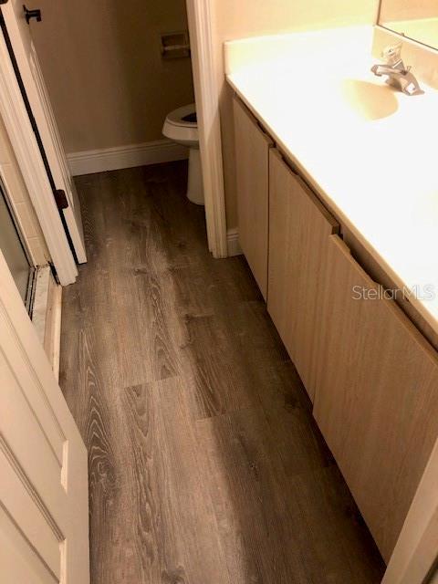 bathroom featuring vanity, wood-type flooring, and toilet