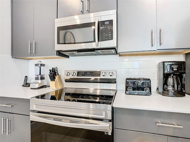 kitchen with stainless steel appliances, tasteful backsplash, and gray cabinetry