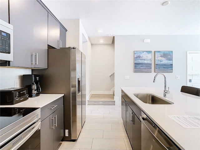 kitchen with range, sink, stainless steel dishwasher, decorative backsplash, and light wood-type flooring