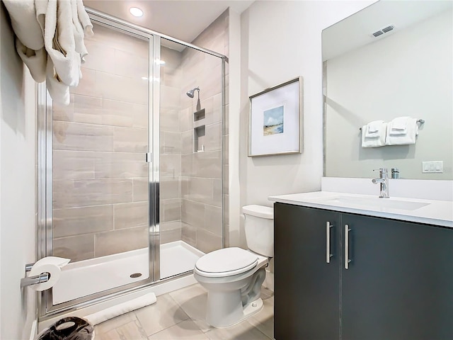 bathroom with a shower with door, vanity, tile patterned flooring, and toilet