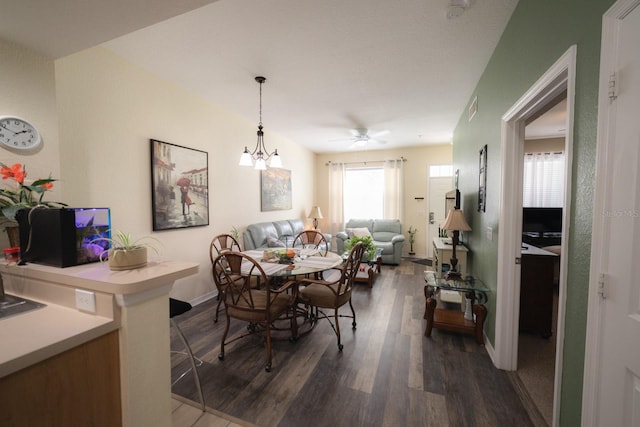 dining space with ceiling fan with notable chandelier and dark hardwood / wood-style floors