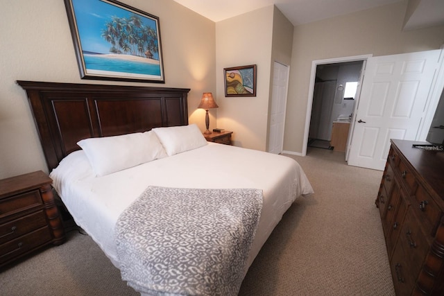 bedroom featuring ensuite bath, light carpet, and a closet