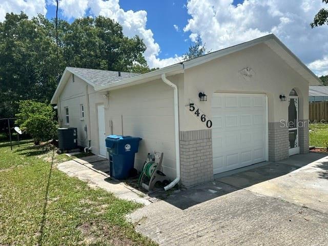 view of side of property with a garage and central AC unit