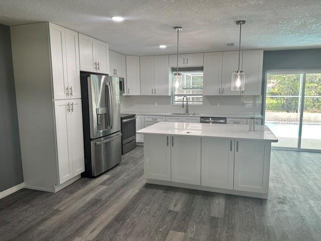 kitchen featuring appliances with stainless steel finishes, a healthy amount of sunlight, sink, and dark wood-type flooring