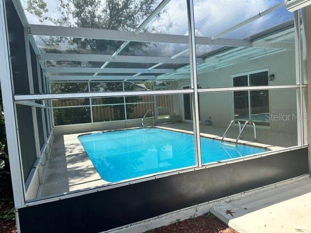 view of swimming pool featuring a lanai and a patio area