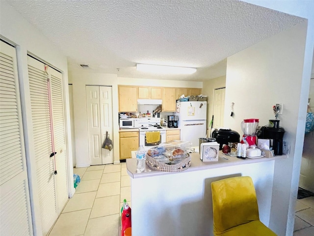 kitchen featuring a textured ceiling, light tile patterned floors, light brown cabinets, and white appliances