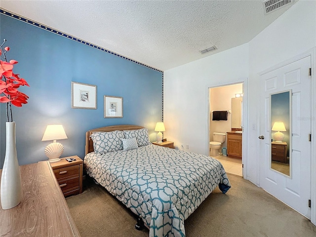 bedroom with a textured ceiling, vaulted ceiling, connected bathroom, and light colored carpet