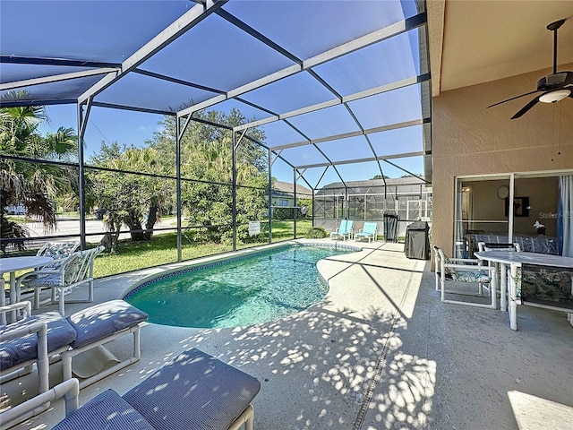 view of pool with a patio, glass enclosure, and ceiling fan