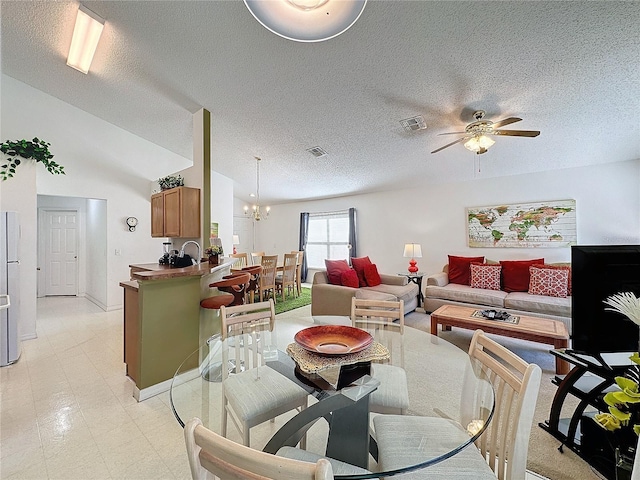 living room with ceiling fan with notable chandelier, vaulted ceiling, and a textured ceiling