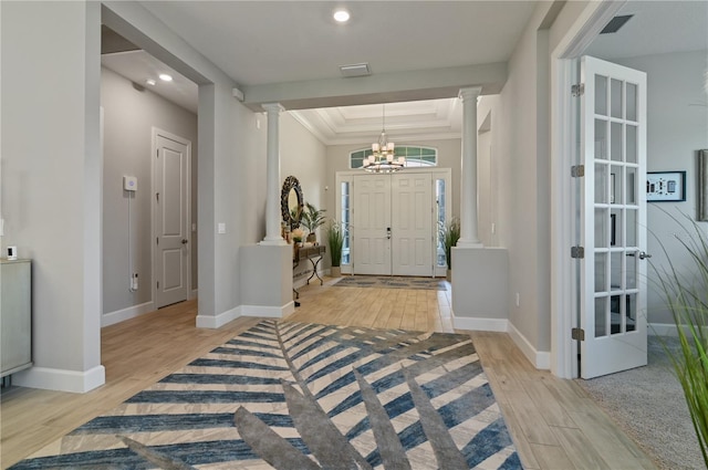 foyer entrance with a chandelier, crown molding, a tray ceiling, and light hardwood / wood-style floors