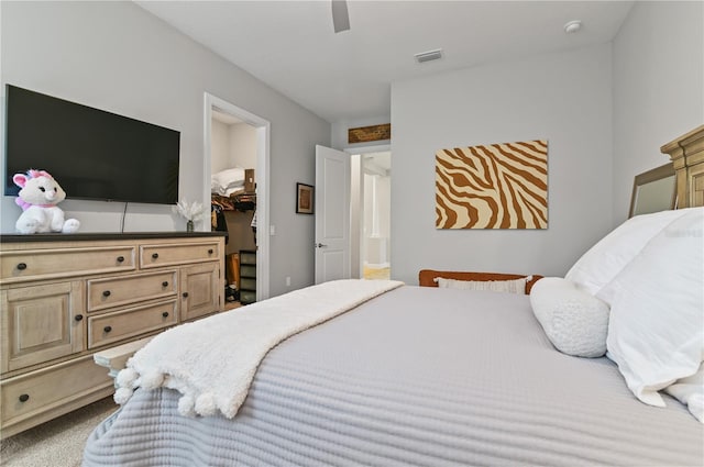 carpeted bedroom with ceiling fan, a spacious closet, and a closet