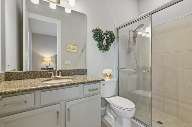 bathroom featuring vanity, toilet, and a shower with shower door