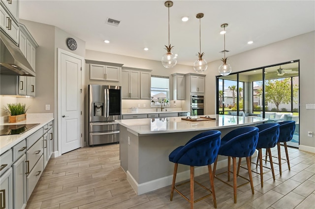 kitchen featuring stainless steel appliances, a kitchen island, and gray cabinetry