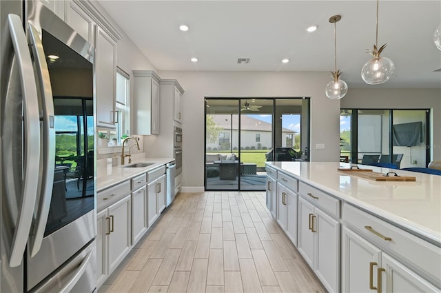 kitchen with white cabinetry, sink, ceiling fan, stainless steel appliances, and pendant lighting