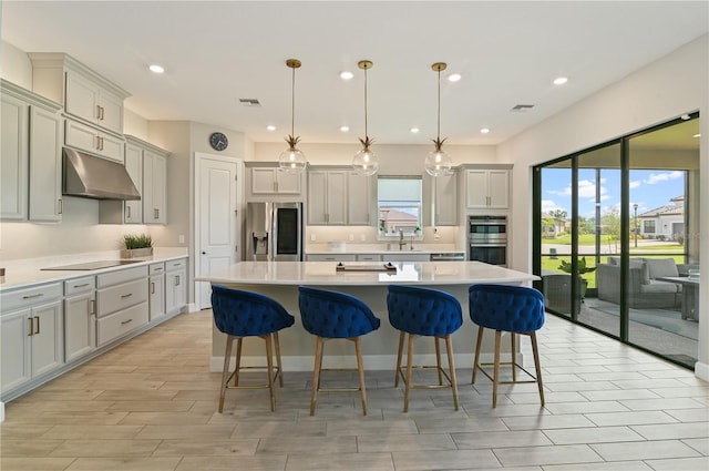 kitchen with decorative light fixtures, a center island, stainless steel appliances, and sink